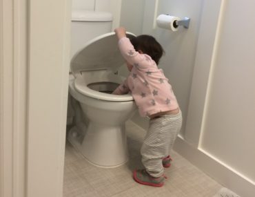 A toddler reaches into the toilet