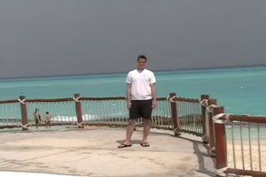  A man stands at a pool in front of a green ocean
